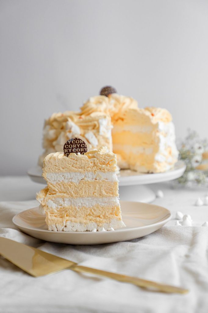 Porción de torta helada sin azúcar de Cory servida en plato, con la torta completa al fondo.